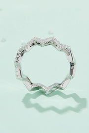 Top-down view of a platinum-tone moissanite ring with a wavy, stone-set band