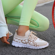 Cream sneakers with tan geometric panels, worn with light green leggings