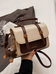 Cream and brown mini flap crossbody bag with top handle and hanging charm