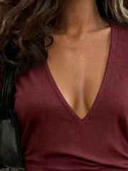 Close-up of the burgundy T-shirt's deep V-neckline and short sleeve.