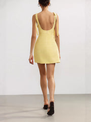 Back view of yellow mini dress showing slim straps and straight back.