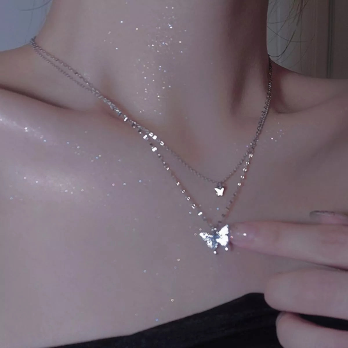 Close view of butterfly pendant necklace worn against a dark top