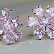 Angled close-up of pink flower earrings showing faceted petals and prong settings