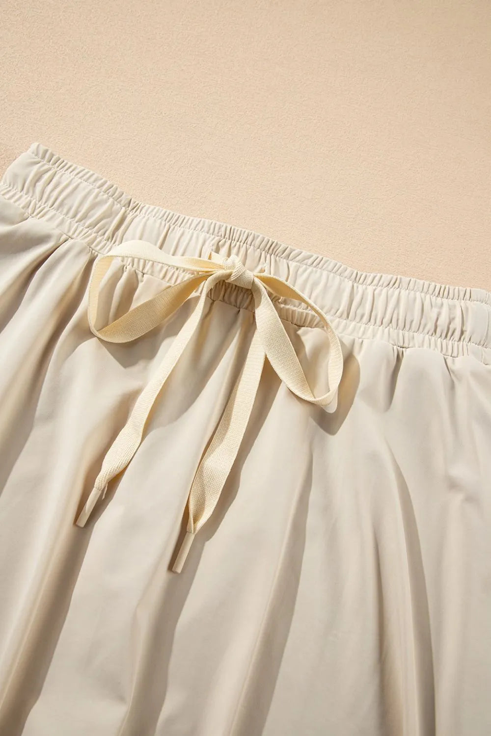 Close-up of the ivory skort's long fabric drawstring and gathered waist.