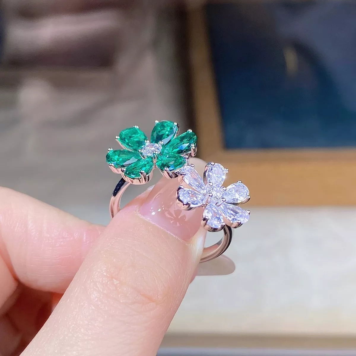 Green and clear flower ring held between fingers, showing both floral settings