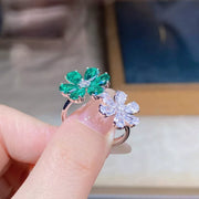 Green and clear flower ring held between fingers, showing both floral settings