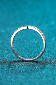 Back view of the plain circular band of a slim moissanite ring on teal.