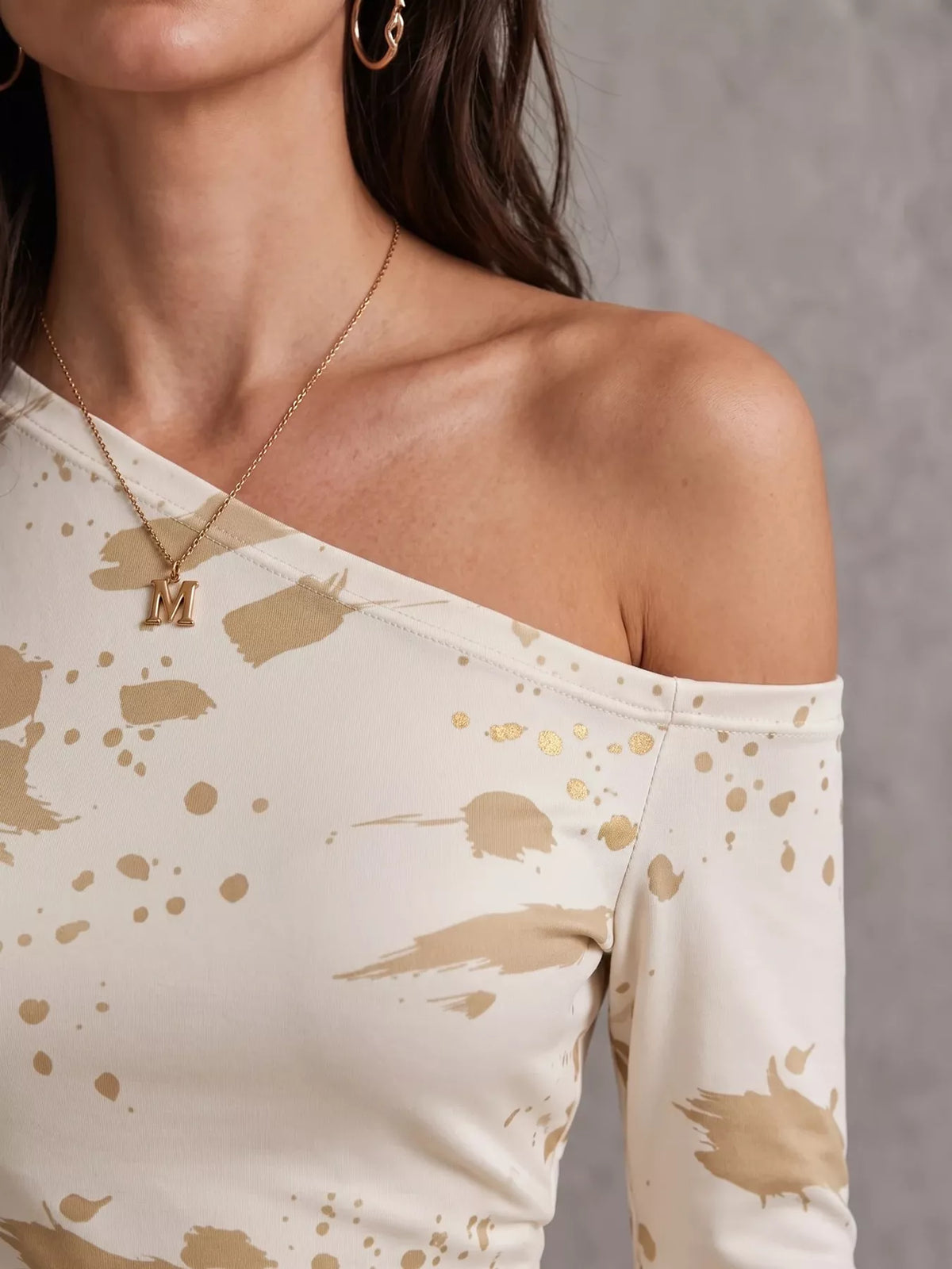 Close-up of the asymmetric neckline and beige splatter pattern on the cream dress
