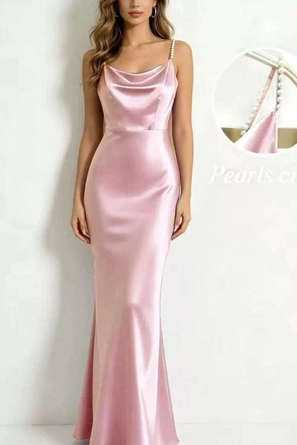 Model wearing a blush pink satin maxi dress with pearl straps and a draped cowl neckline.