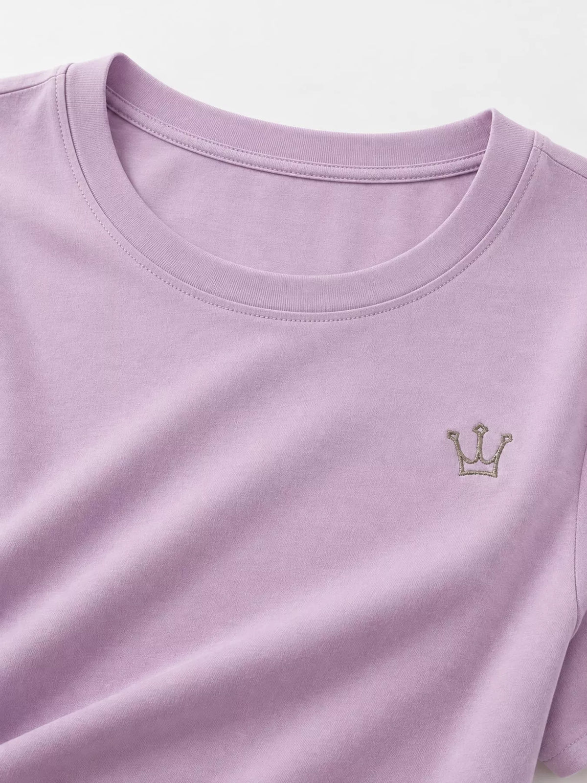 Close-up of lavender T-shirt neckline and small crown emblem.