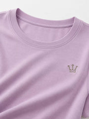 Close-up of lavender T-shirt neckline and small crown emblem.