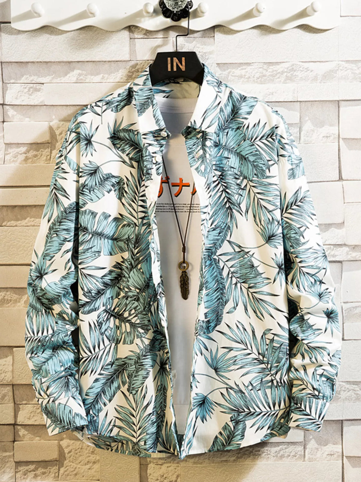 Front view of a white shirt with blue-green tropical leaf print