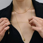 Model holds the long Y necklace to show its drop length and two gold charms