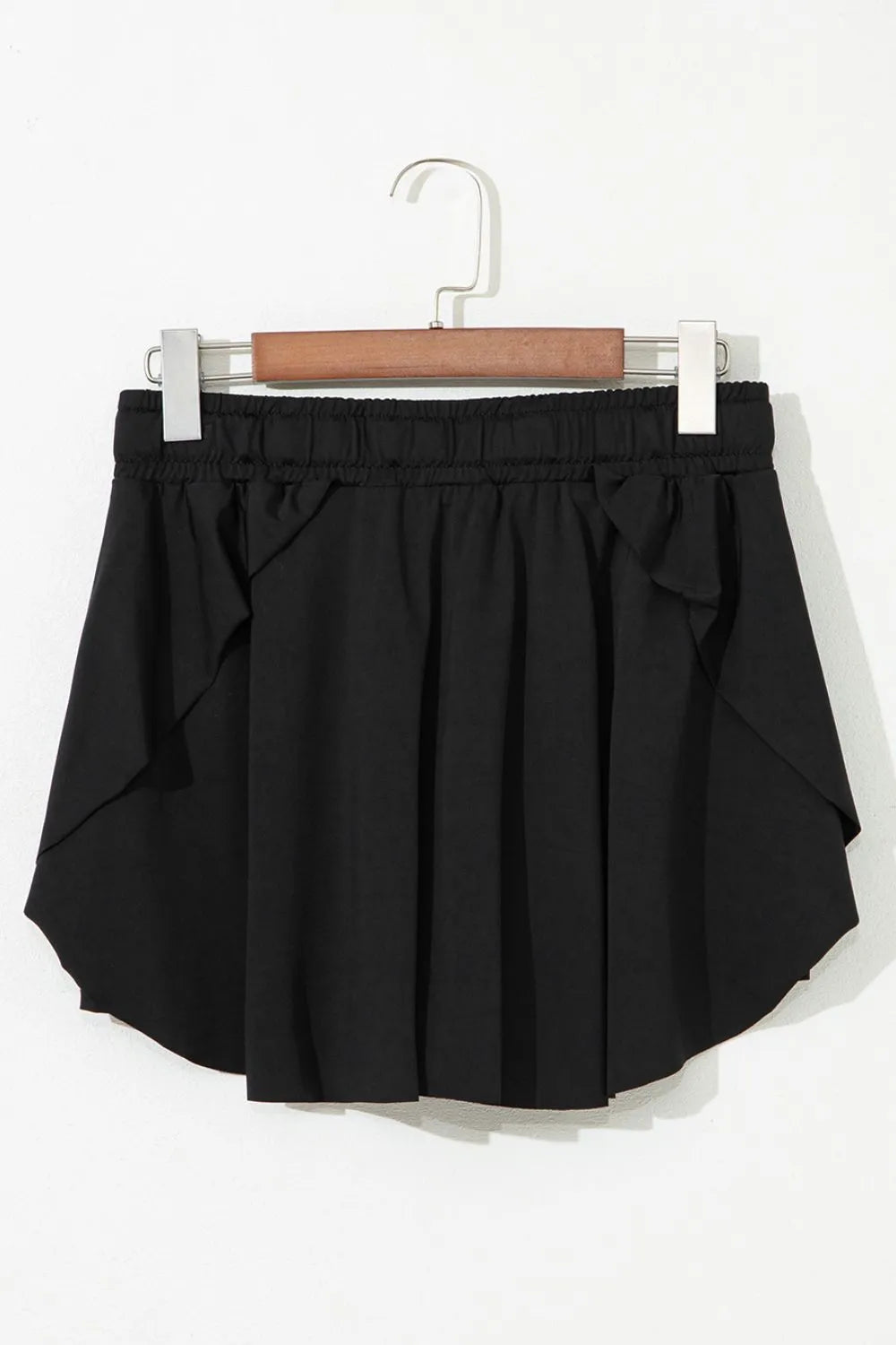 Black skort displayed on a hanger, showing the back and layered hem