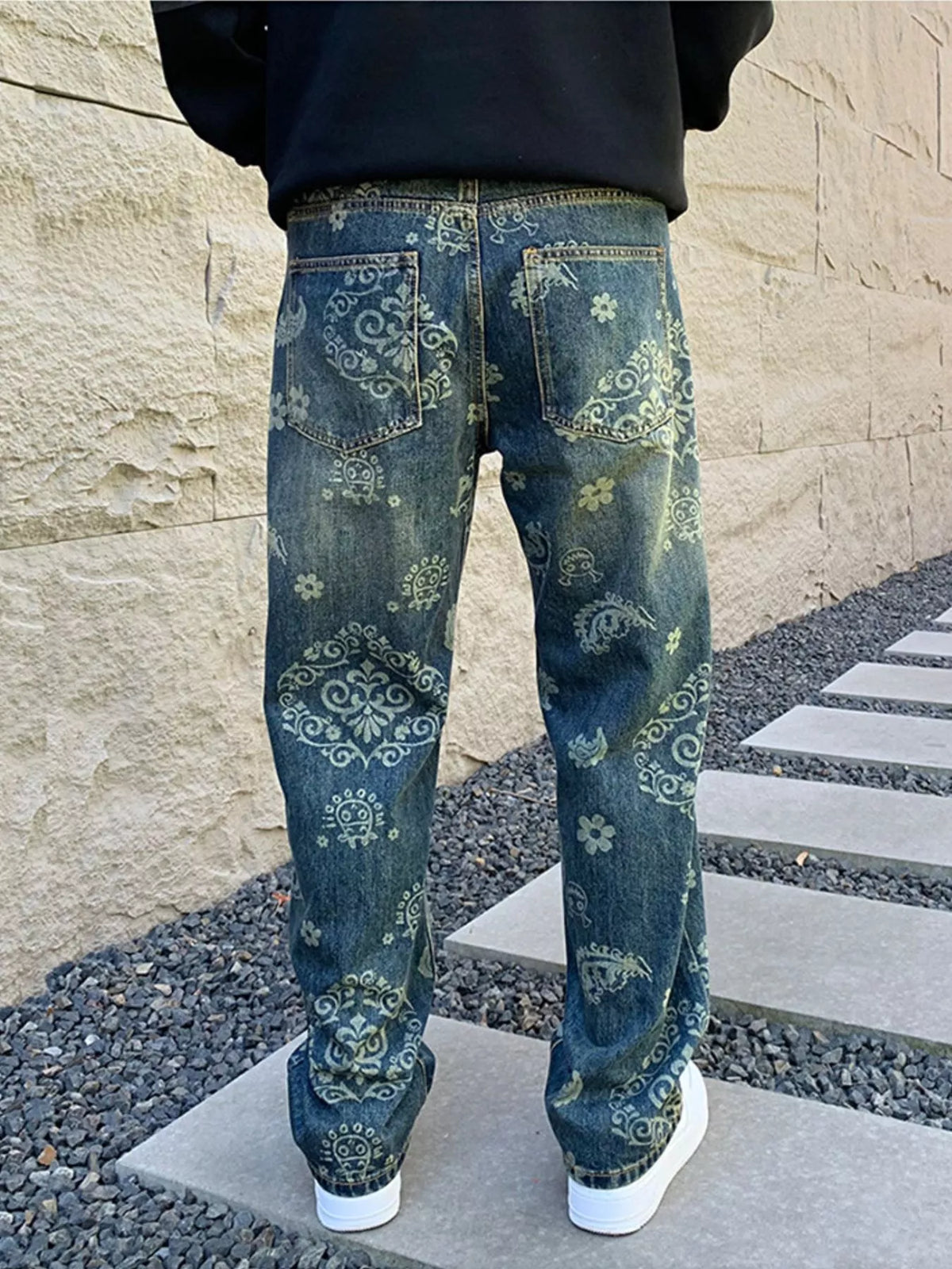 Straight back view of loose blue jeans with ornamental patterns