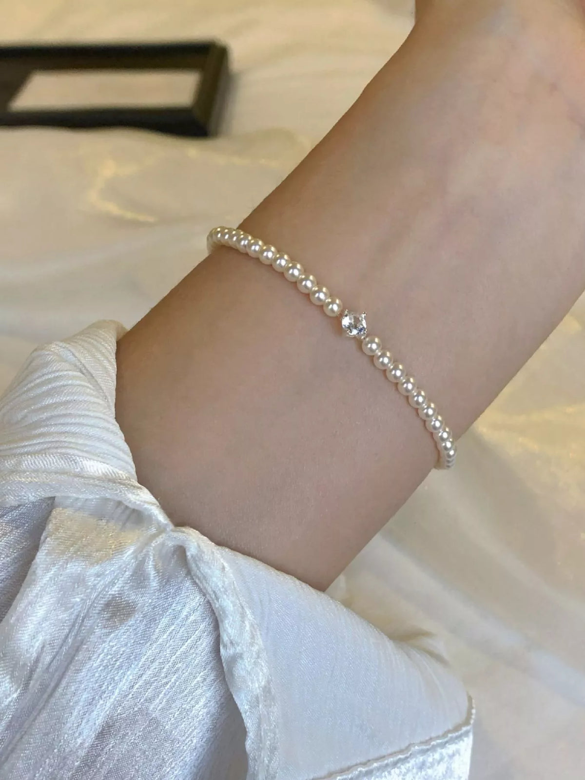 Pearl bracelet worn around the wrist, shown beside an open jewelry box.