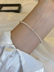 Pearl bracelet worn around the wrist, shown beside an open jewelry box.