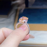 Side view of the oval pink gemstone ring held between fingers