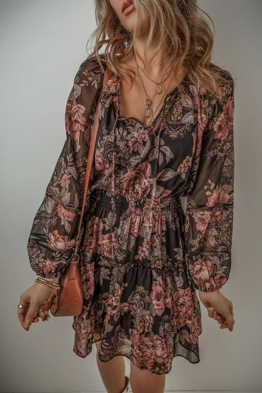 Model wearing a dark floral mini dress with a tie neckline and long sleeves, front view