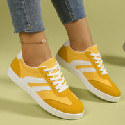 Yellow flat shoes with white curved stripes worn with jeans