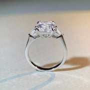 White-metal ring with a large clear emerald-cut center stone, viewed from the side to show the setting