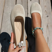 Ivory mesh flat held beside a matching shoe, showing the insole
