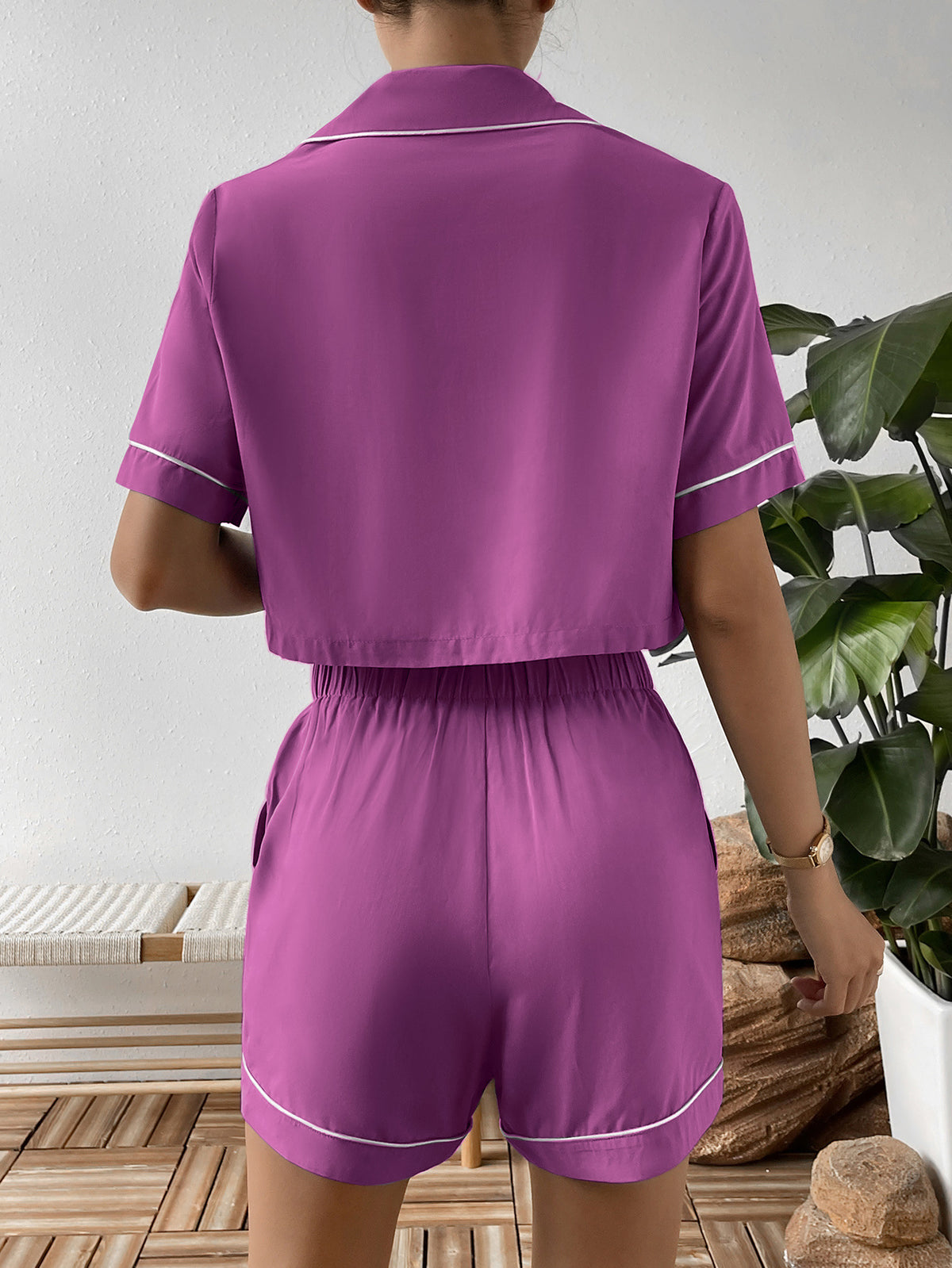 Back view of purple cropped shirt and matching shorts with white piping