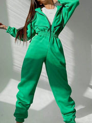 Women's green hooded jumpsuit, model front view with one arm extended