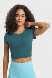 Model posing in deep teal cropped T-shirt and light blue leggings