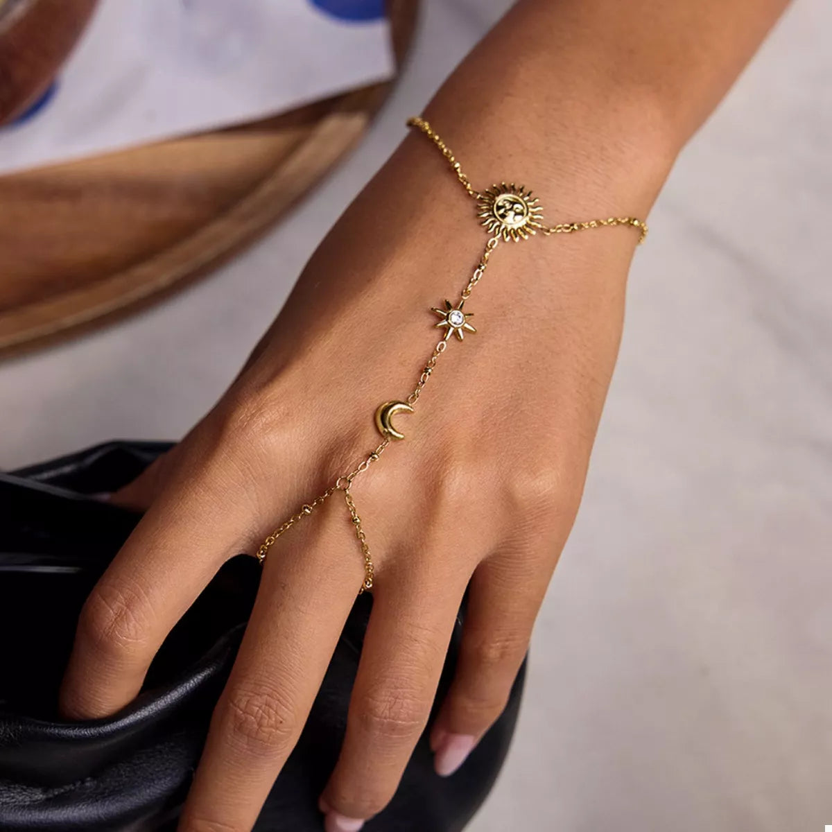Gold sun charm bracelet displayed on a white surface