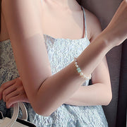 Close view of the pearl and green stone bracelet worn with a light outfit
