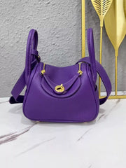 Front view of a purple crossbody bag with gold-tone turn lock