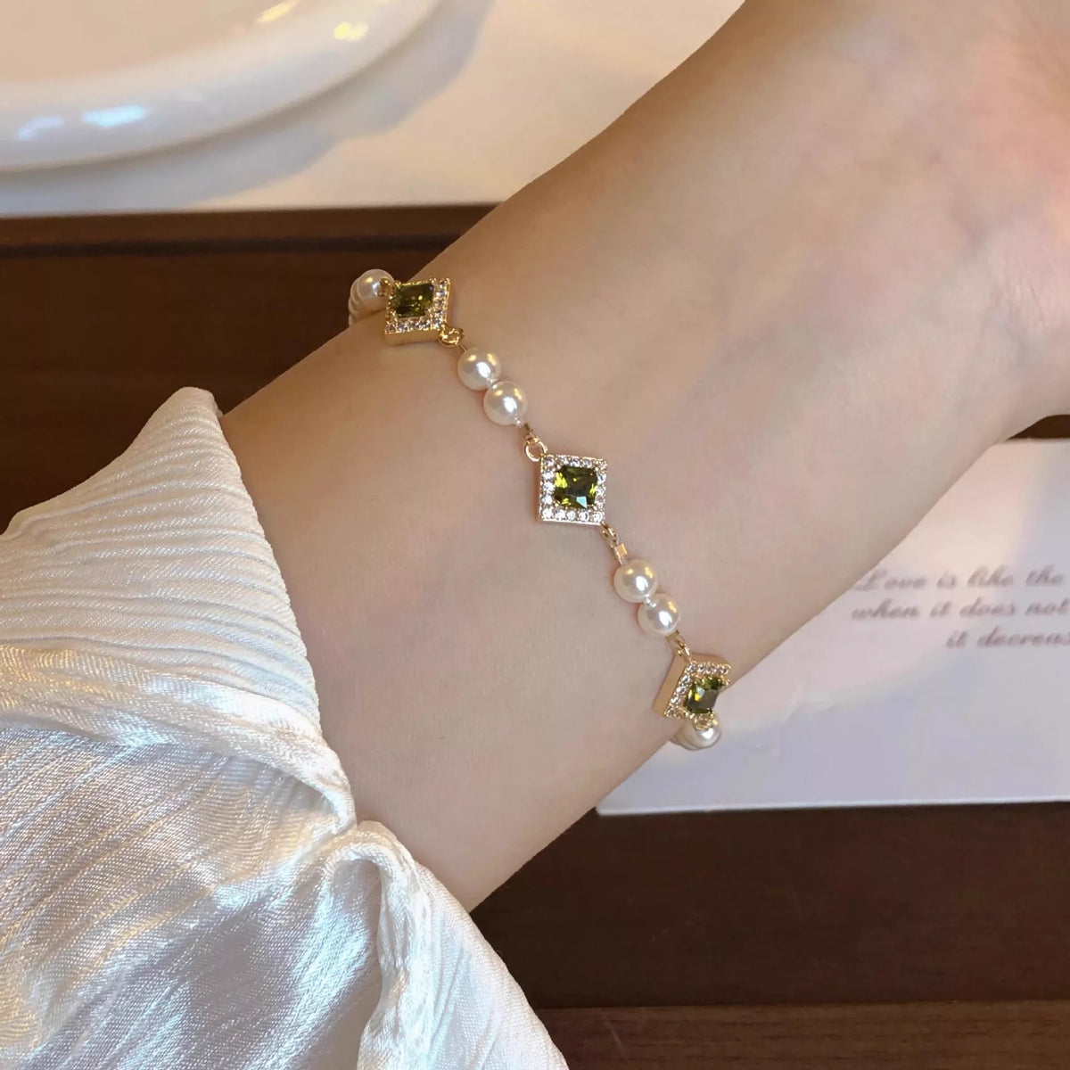 Gold-tone geometric pearl and zircon bracelet worn on wrist