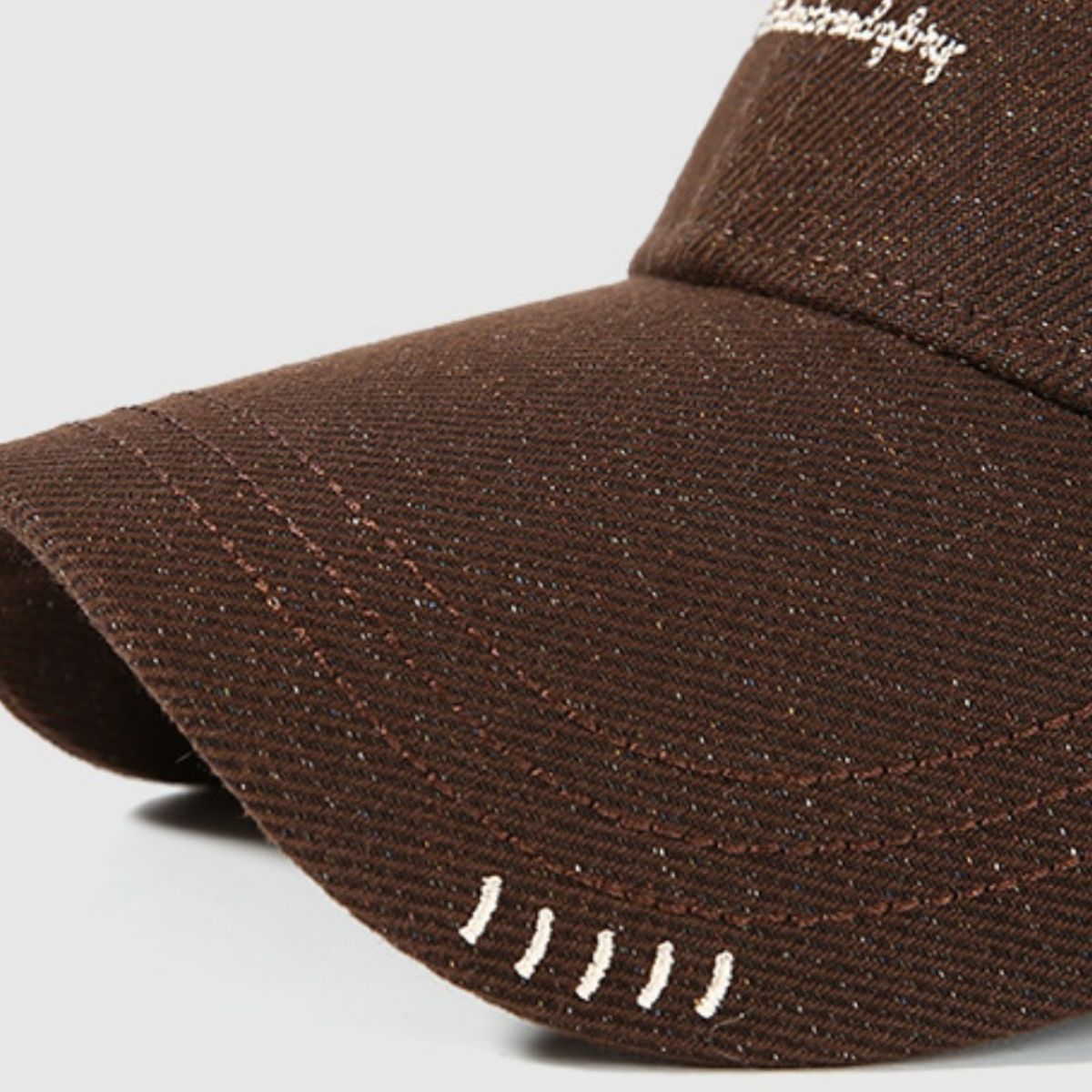 Close-up of the brown cap's curved brim and stitched detailing