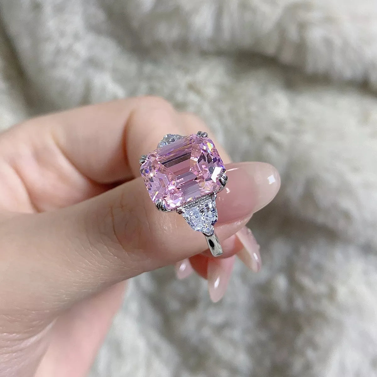 Side view of a blush pink rectangular zircon ring held between fingers