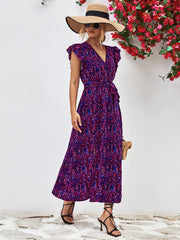 Front view of purple printed dress with V-neck, flutter sleeves and long straight skirt.