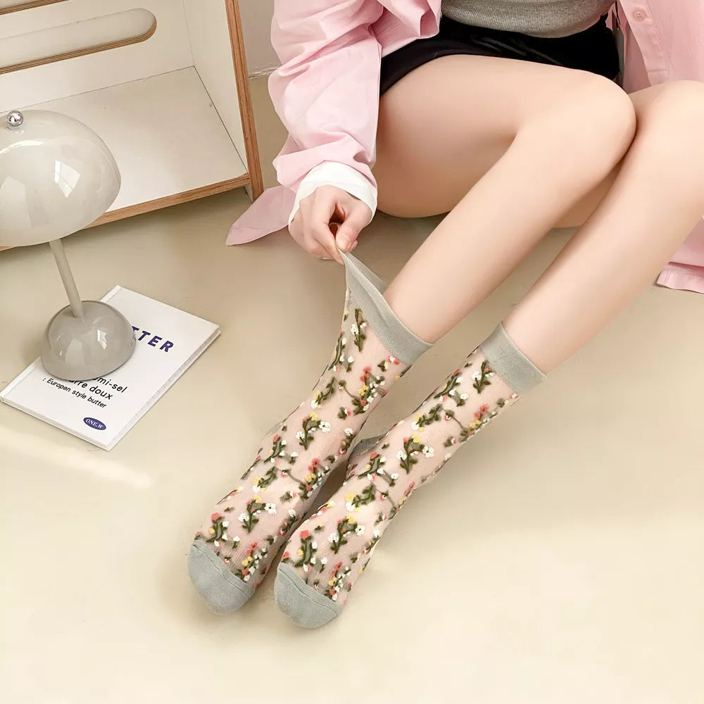 Light floral sheer socks with blue-gray cuffs and toes shown close up on legs