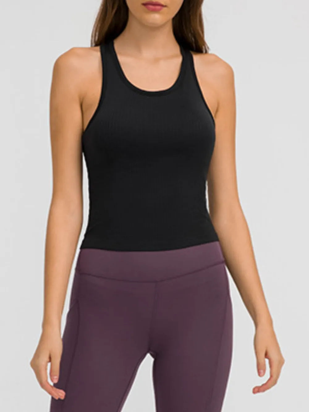 Model wearing black racerback tank with plum leggings