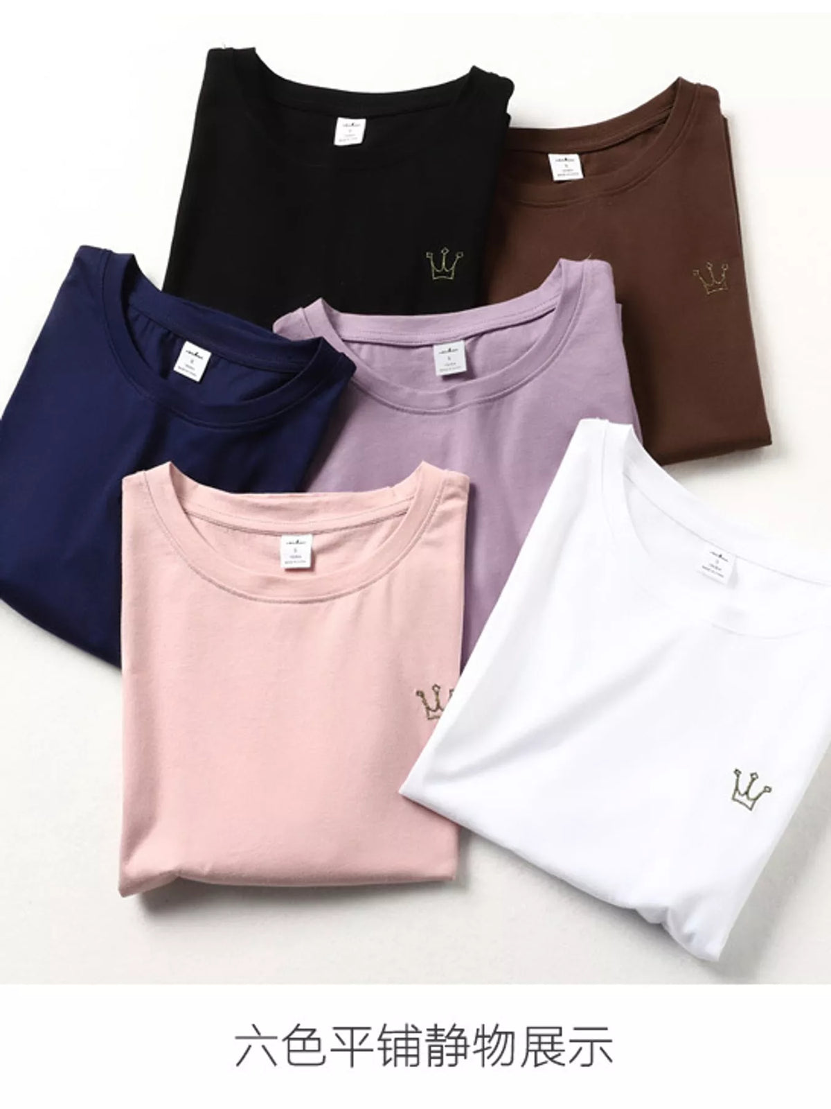 Six folded crewneck T-shirts in black, brown, navy, lavender, pink and white, each with a small crown emblem.