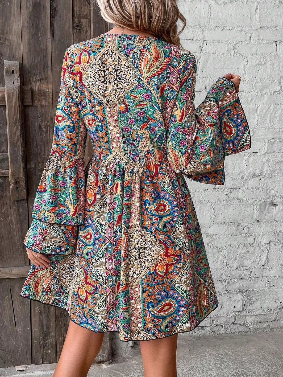 Back view of paisley print mini dress with bell sleeves