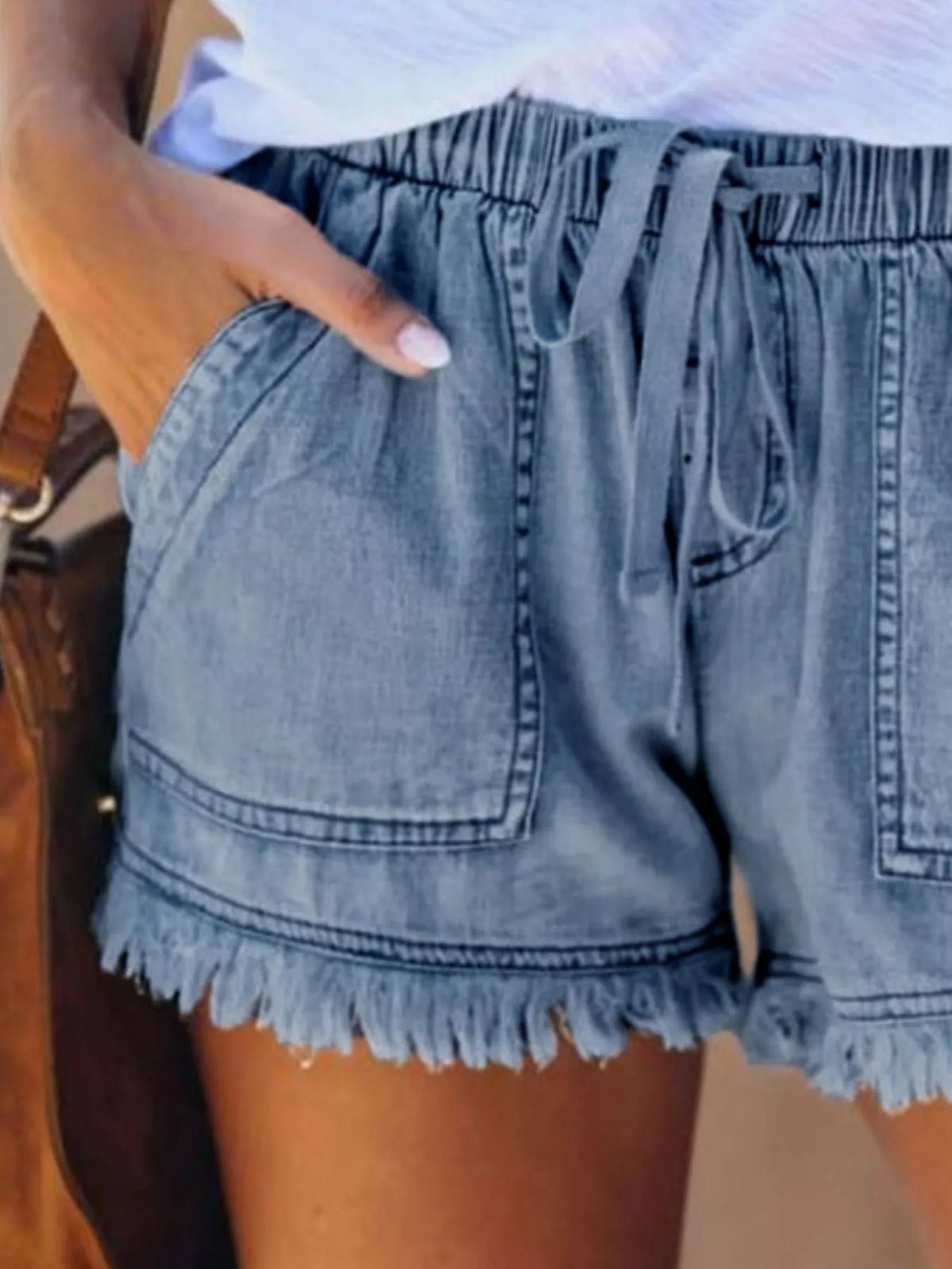 Close view of light blue drawstring denim shorts and their large front patch pockets