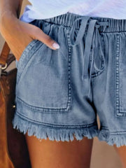 Close view of light blue drawstring denim shorts and their large front patch pockets