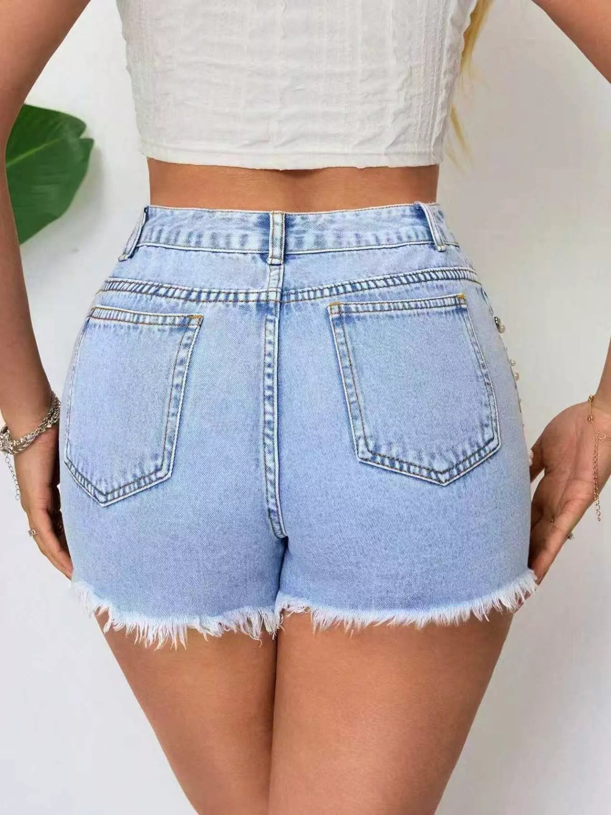 Back view of light-wash denim shorts with two pockets and frayed hems