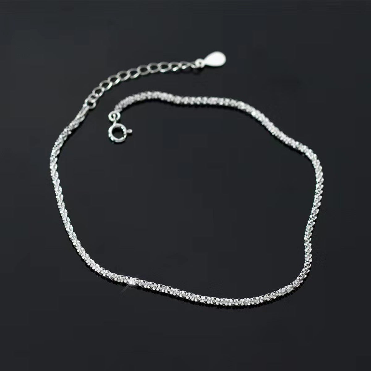 Sterling silver chain bracelet laid out in a rounded loop