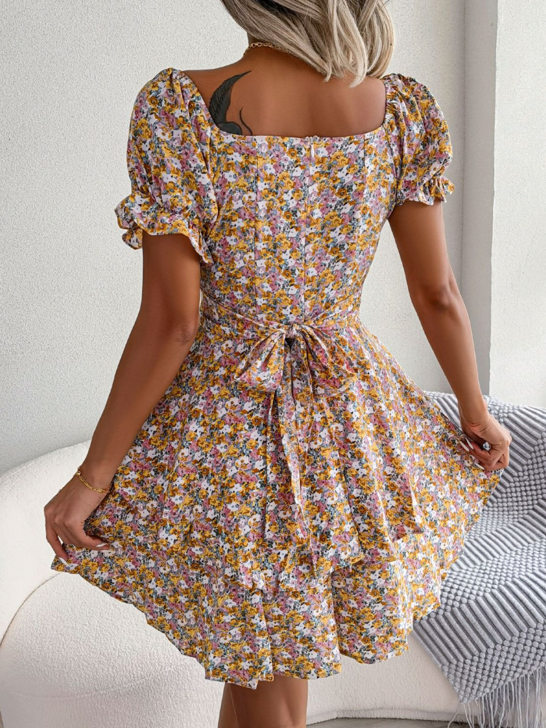 Rear view of yellow floral mini dress with flared skirt and short sleeves