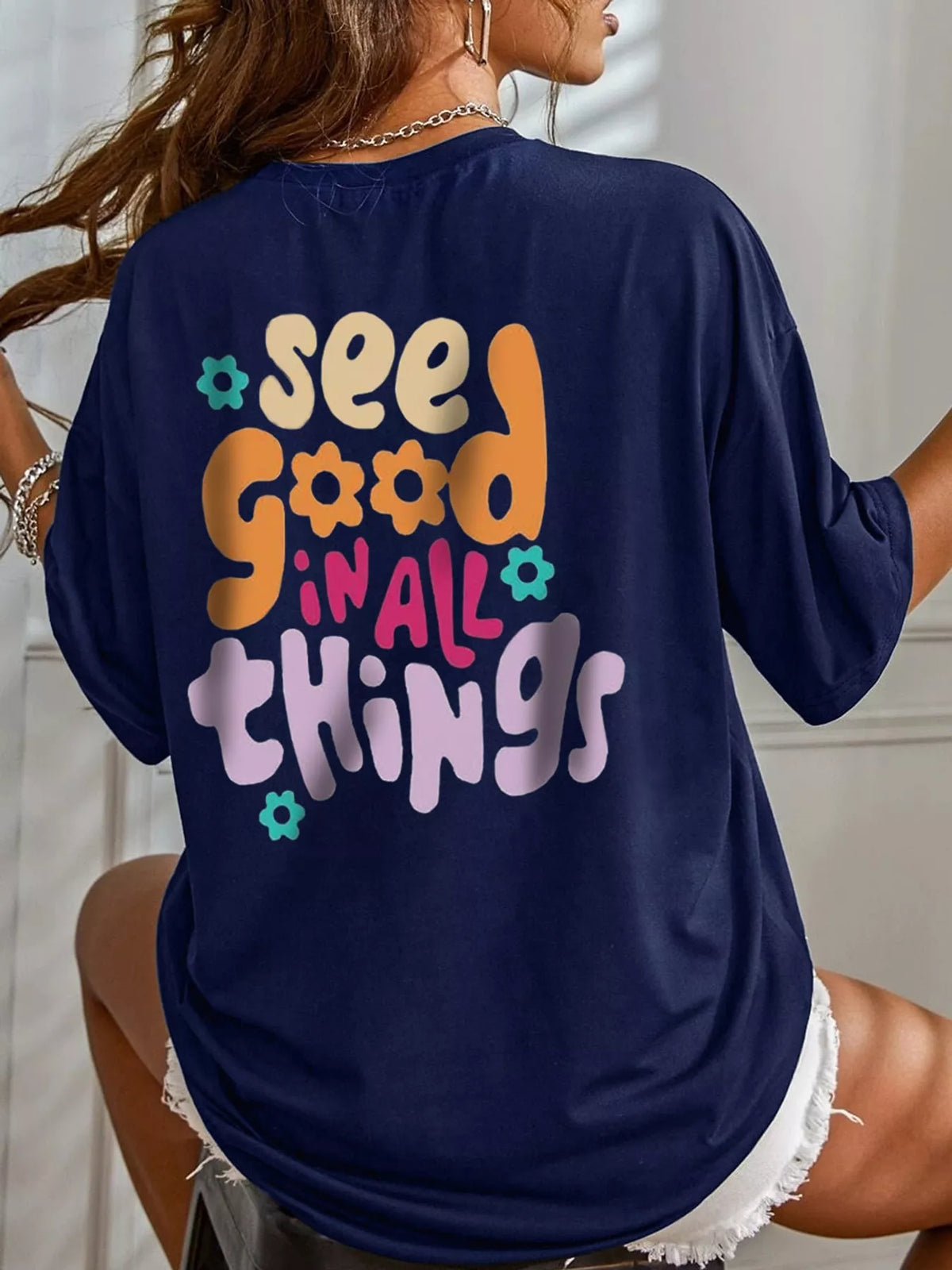 Back view of a navy oversized T-shirt with a colorful text-and-flower graphic