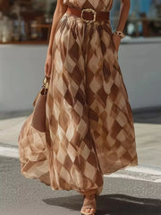 Lower half of the flowing brown diamond-print maxi dress shown with the belt and woven handbag.