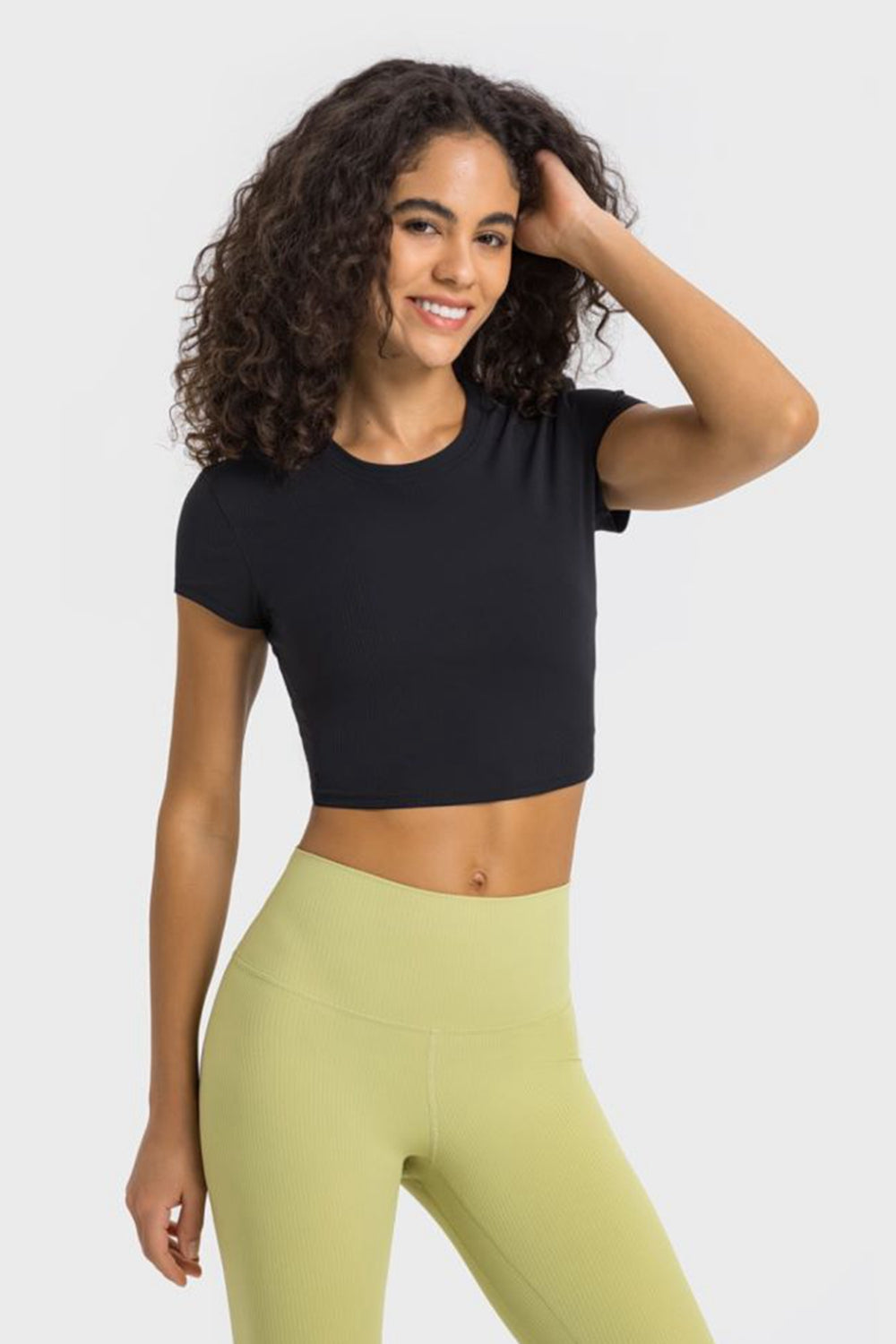 Model posing in a black cropped T-shirt and pale yellow leggings