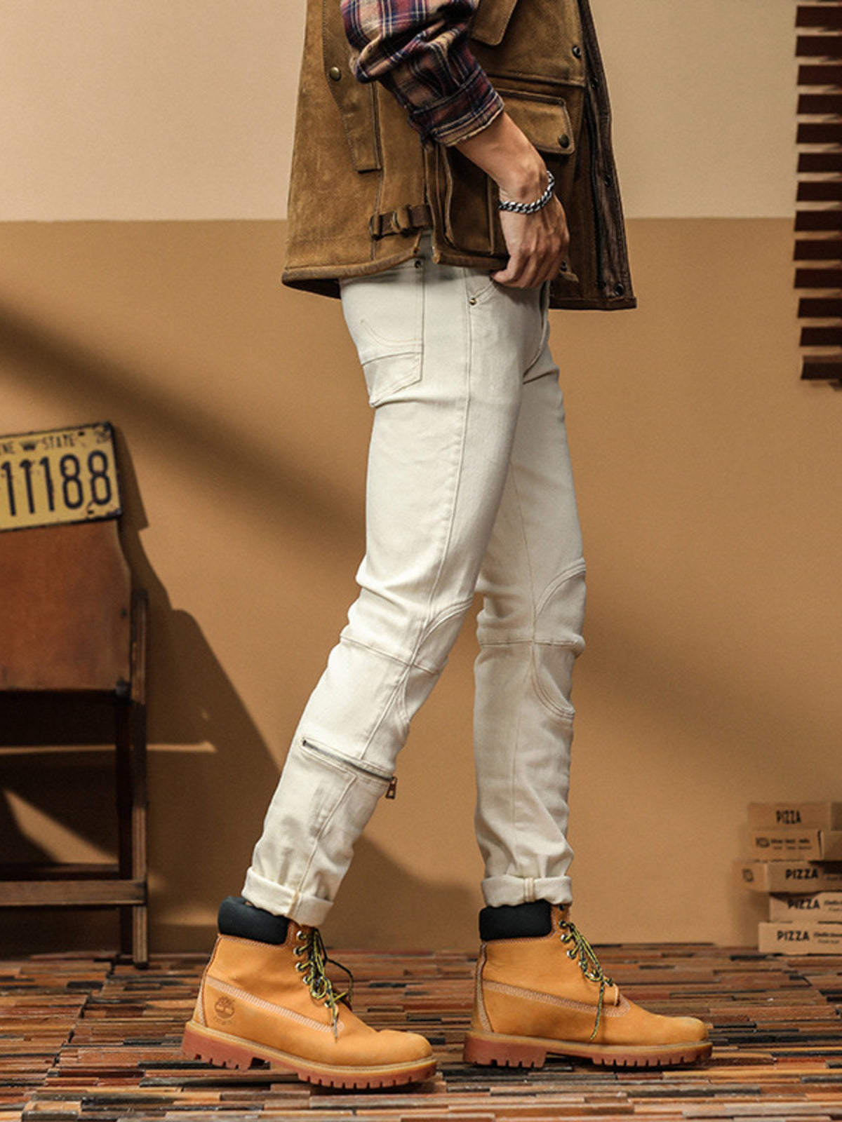 Side view of off-white slim-fit jeans showing knee panels and a lower-leg zip