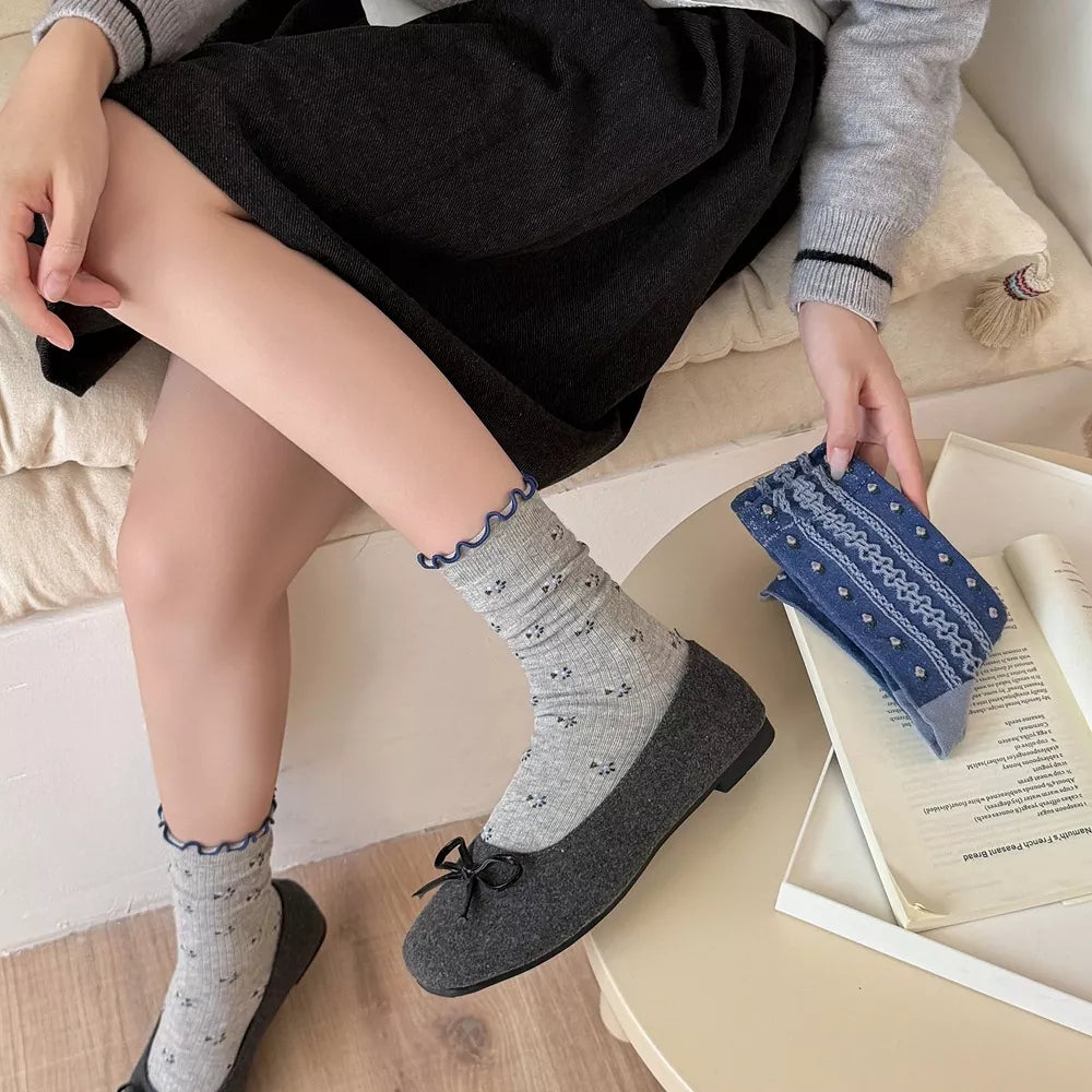 Gray patterned socks with navy scalloped cuffs shown worn with a dark skirt and loafers